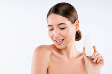 Beyaz arka planda plastik bir şişe yoğurt tutan güzel bir kadın.