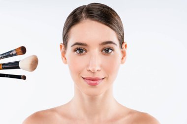 Beyaz arka planda izole edilmiş makyaj fırçaları olan güzel genç bir kadının portresi.