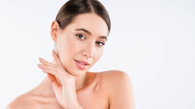 Beyaz arka planda izole edilmiş kameraya bakan mükemmel ciltli, yarı çıplak genç bir kadının portresi.