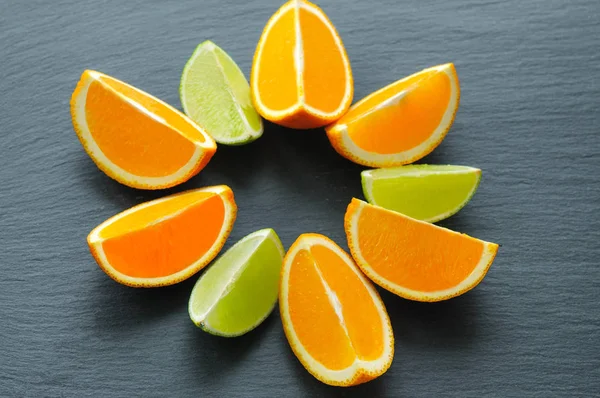 Orange and lime sliced segments on black slate stone. Vitamin concept — Stock Photo, Image