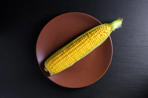 Oor van maïs op bruin plaat. Concept bovenaanzicht — Stockfoto