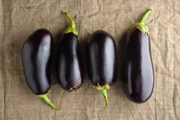 Vier reife schwarze Auberginen auf Leinentuch. rustikale Draufsicht — Stockfoto