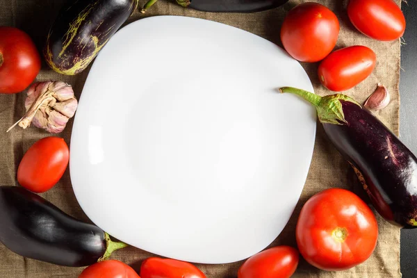 Leerer weißer Teller in der Mitte und Gemüse herum. Kopierraum. — Stockfoto