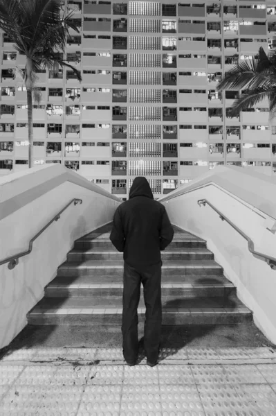 Rejtélyes ember áll a toronyház előtt, aki éjjel egy Hong Kong-i közbirtokon nyüzsög. — Stock Fotó