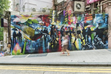 Hong Kong, Çin - 27 Eylül 2018: Hong Kong şehrinde renkli grafitilerin önünde yürüyen bulanık yaya