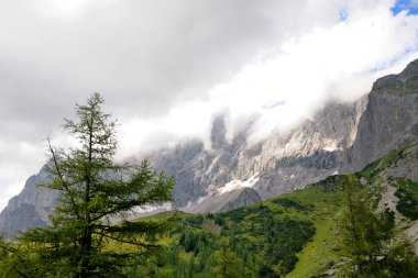 Yüksek dağ sıraları, tepede kar. Dağları kaplayan beyaz bulutlar.
