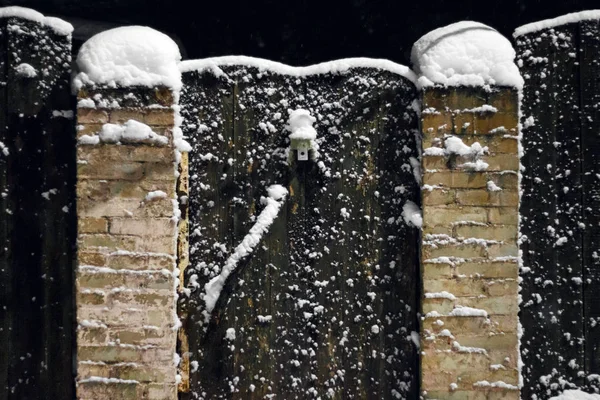 Snow covered wooden fence and door close-up