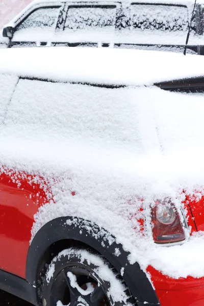 Pokryte śniegiem czerwony samochód na parkingu w zimie — Zdjęcie stockowe