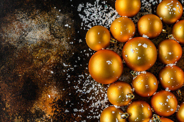 Beautiful christmas and new year golden deco baubles with white snowflakes on dark black background. Selective focus. Flat lay design. Copy Space