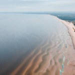 Aerialphoto of the Baltic sea beach. Azure waves, sand ridges, footprints in the sand.