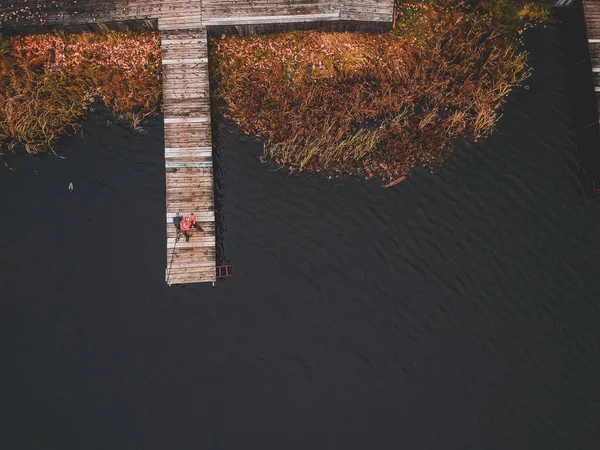 Rıhtımda elinde olta olan bir balıkçının göl kıyısı, sonbahar ormanı. Finlandiya. — Stok fotoğraf