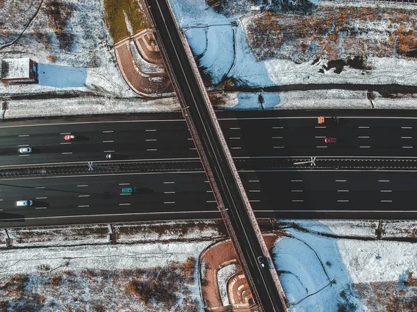Luchtfoto van landweg en brug, wegverkeer, besneeuwde bossen en velden, winter. Rusland, Sint-Petersburg. — Stockfoto