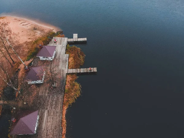 Luftaufnahme eines Fischers mit Angelrute auf der Seebrücke, Seeufer, Herbstwald. Finnland. — Stockfoto