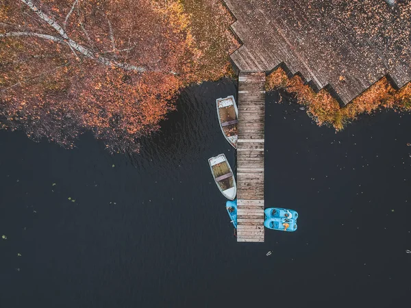 Aerial view pier with wooden boats on the shore of a picturesque lake, autumn forest. St. Petersburg, Russia. — Free Stock Photo