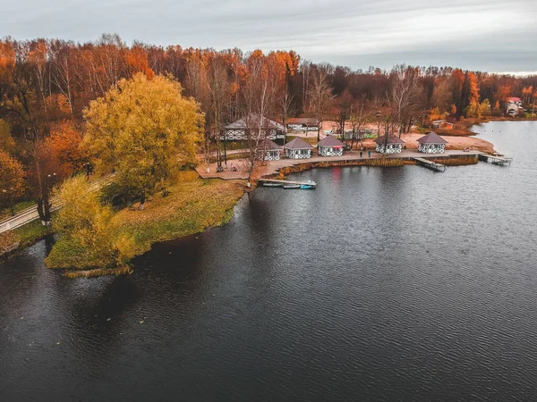 Aerial view of forest and blue lake. Sauna house by the lake shore. Wooden pier with fishing boats. St. Petersburg, Russia. — Stock Photo, Image