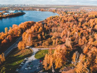 Ormanın sabah ışıklarındaki hava manzarası. Renkli ağaçlar ve yukarıdan mavi göl, dolambaçlı yol. Rusya, St. Petersburg