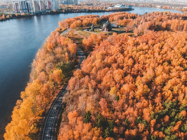 Flygfoto på morgonbelysning i skogen. Färgglada träd och blå sjö uppifrån, slingrande väg. Ryssland, Sankt Petersburg — Stockfoto