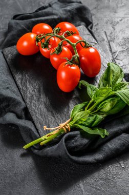Siyah arka planda fesleğenli kiraz domatesleri. Üst görünüm.