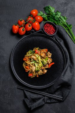 Kızarmış erişte, geleneksel Çin tavası. Yemek çubukları, malzemeler. Sebzeli Asya eriştesi, et. Siyah siyah arka plan. Üst görünüm.