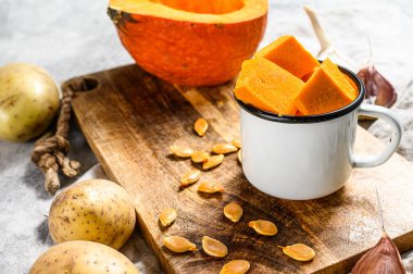 Balkabağı çorbası için malzemeler. Gri arka plan. Kırsal kesim tahtasında doğranmış balkabağı. Lezzetli ve sağlıklı yiyecekler. Vejetaryen yemeği