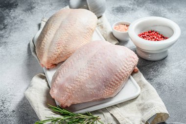 Beyaz kesim tahtasında çiğ tavuk göğsü. Organik çiftlik kuşu. Taze fileto. Gri arkaplan