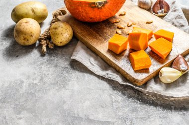 Balkabağı çorbası için malzemeler. Mesaj için yer var. Gri arka plan. Kırsal kesim tahtasında doğranmış balkabağı. Lezzetli ve sağlıklı yiyecekler. Vejetaryen yemeği