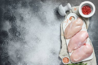 Beyaz kesim tahtasında çiğ tavuk göğsü. Organik çiftlik kuşu. Taze fileto. Gri arka plan. Metin için boşluk