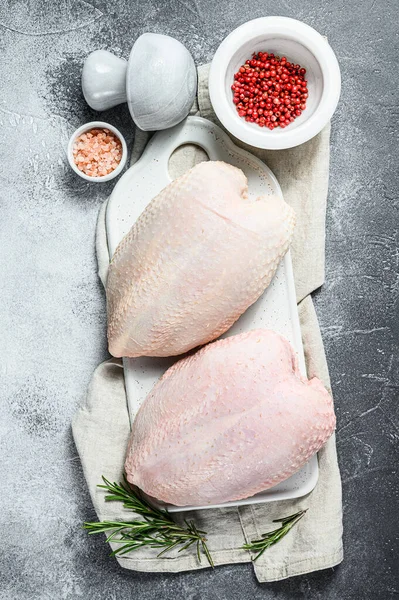 Petti di pollo crudo su un tagliere bianco. Uccello da fattoria biologico. Filetto fresco con pelle. Fondo grigio — Foto Stock