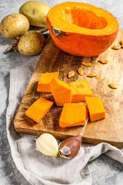 Ingredients for pumpkin soup. Pumpkin pieces on a cutting Board. Cream soup. Gray background. Vegetarian cuisine