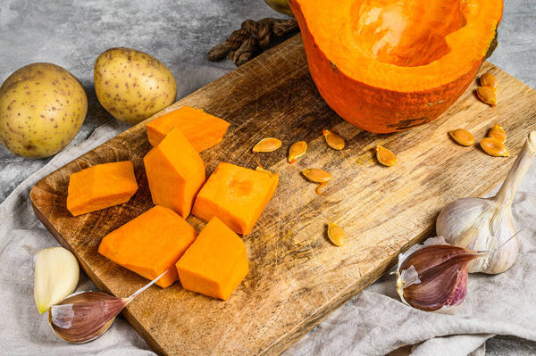 Ingredients for pumpkin soup. Gray background. Chopped Pumpkin on rustic cutting board. Tasty and healthy food. Vegan food