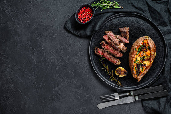Marbled beef steak with baked sweet potato garnish. Grilled meat. Organic farm meat. Black background. Space for text.