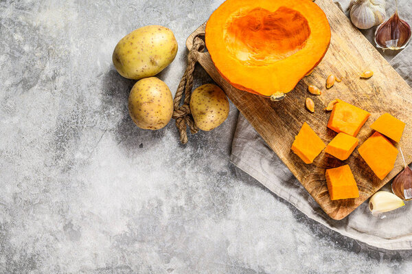 Ingredients for pumpkin soup. Space for text. Gray background. Chopped Pumpkin on rustic cutting board. Tasty and healthy food. Vegan food