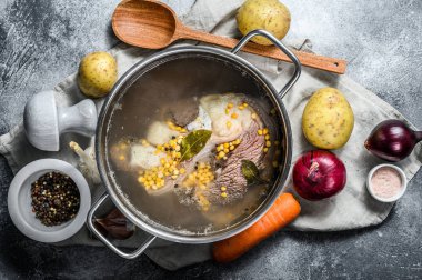 Kemik çorbası ile tencere pişiriyorum. Sebzeler mutfak masasında baharat ve malzeme pişiriyor. Üst görünüm