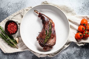 Taze domates ve biberiyeyle servis edilen çiftlik tavşan bacağı güveci. Gri arka plan. Üst görünüm