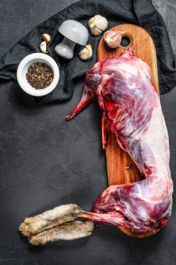 Tüm orman yaban tavşanı, ahşap güvertede çiğ et, eski siyah kırsal masa. Üst görünüm, boşluk kopyala