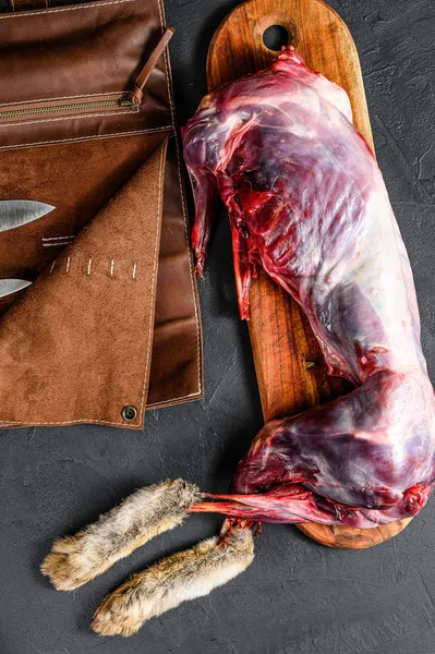 stock image Whole forest farm rabbit, raw meat on wooden deck, old black rustic table. top view