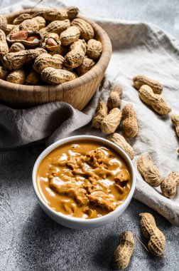 Fıstık ezmesi ve çiğ fıstık. Sağlıklı vejetaryen yemekleri. Gri arka plan. Üst görünüm.