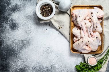 Tahta bir kasede çiğ tavuk kanadı. Üst Manzara. Gri arka plan. Metin için boşluk