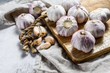 Tahta kesme tahtasına sarımsak soğanı ve sarımsaklı karanfil. Organik tarım yiyeceği. Gri arka plan. Üst Manzara. Kapat.