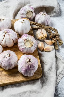 Tahta kesme tahtasına sarımsak soğanı ve sarımsaklı karanfil. Sağlıklı beslenme kavramı. Gri arka plan. Üst görünüm