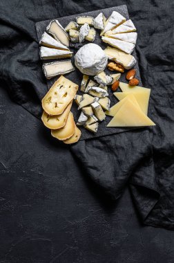 Cheese plate served with nuts and figs. Black background. Top view. Space for text clipart