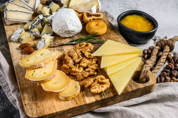 Sortiment französischer Käse mit Honig, Nüssen und Feigen auf Schneidebrett. grauer Hintergrund. Ansicht von oben. — Stockfoto