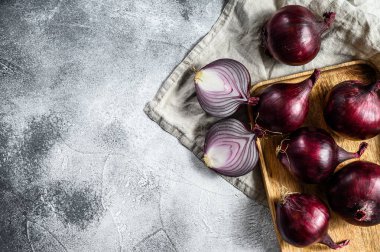 Tahta bir kasede kırmızı soğan, soğan yarımları. Çiftlik sebzeleri. Gri arka plan. Üst Manzara. Metin için boşluk