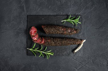 Fuet, Salam ve biberiye filizi. Geleneksel İspanyol sosisi. Siyah arka plan. Üst görünüm