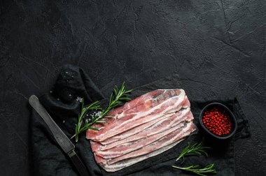 Taş doğrama tahtasında çiğ domuz pastırması. Domuz eti. Siyah arka plan. Üst Manzara. Metin için boşluk