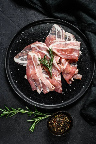 Pork bacon on a black plate. Farm organic meat. Black background. Top view — Stock Photo, Image