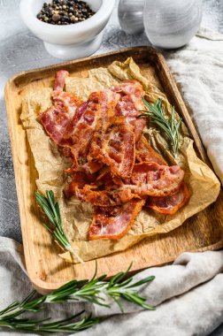 Ahşap doğrama tahtasında kızarmış pastırma. Biberiye ve karabiberle servis et. Gri arka plan. Üst görünüm