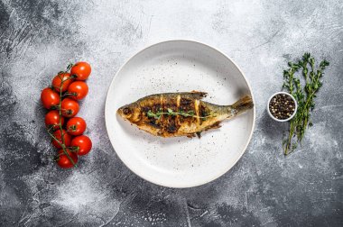 Beyaz tabakta kızarmış sazan balığı. Nehir organik balığı. Gri arka plan. Üst görünüm