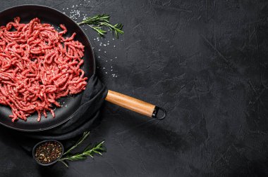 Kızartma tavasında çiğ mermer biftek. Siyah arka plan. Üst Manzara. Metin için boşluk