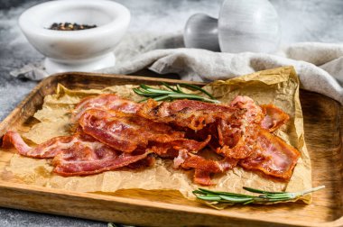 Ahşap doğrama tahtasında kızarmış pastırma. Biberiye ve karabiberle servis et. Gri arka plan. Üst görünüm